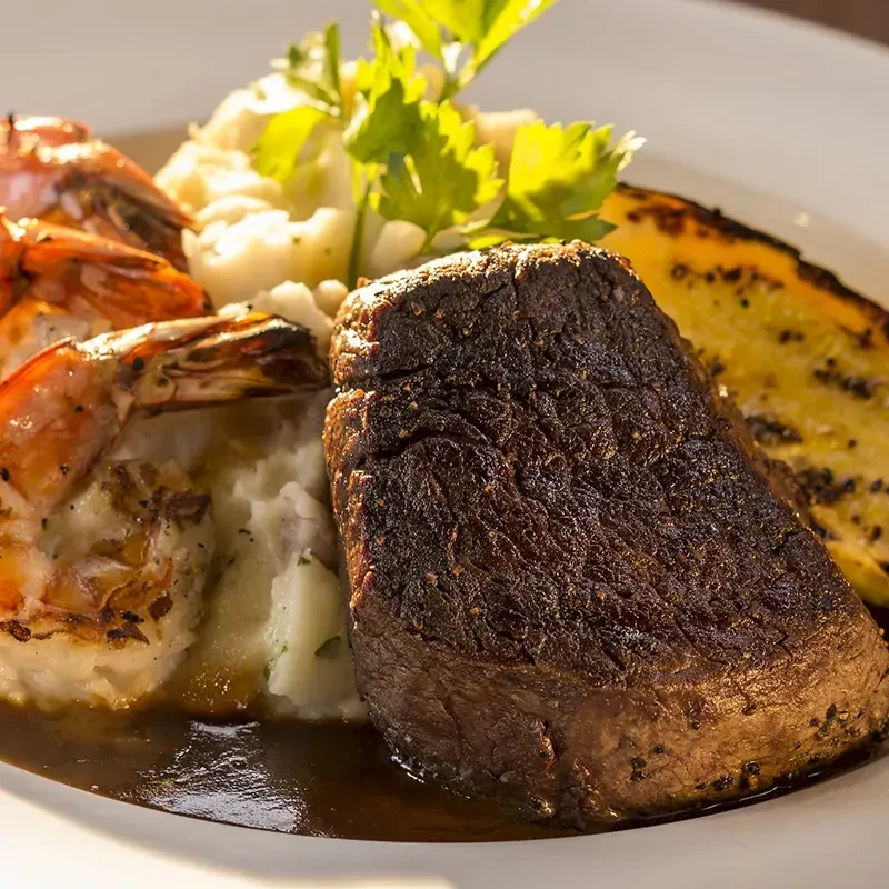 Seared steak, mashed potatoes, grilled shrimp, squash, and brown sauce.