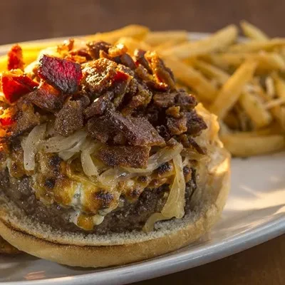 Hamburger with melted cheese, crispy bacon, caramelized onions, and fries.