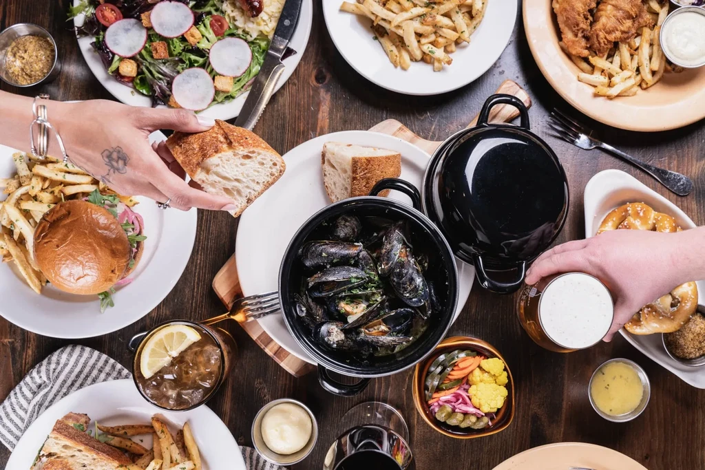 High-angle view of a vibrant table laden with food, drinks, and hands.