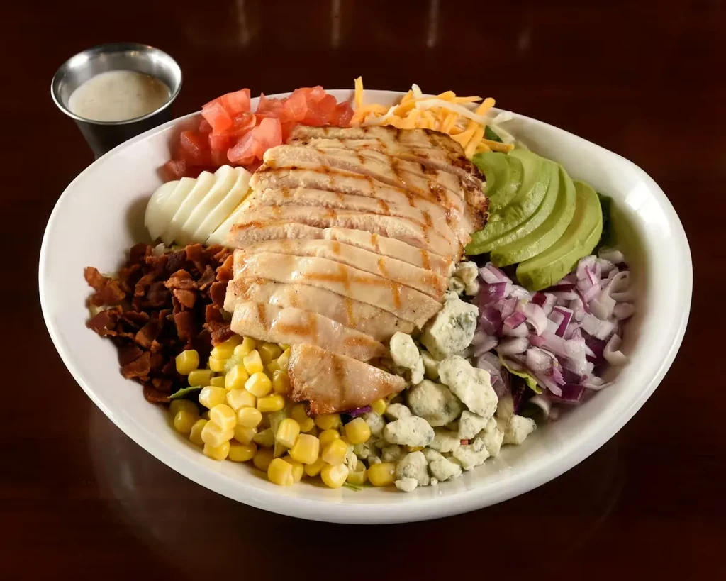 Colorful Cobb salad with grilled chicken, avocado, eggs, and dressing.
