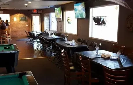 Casual sports bar interior with event tables, pool tables, and TVs.