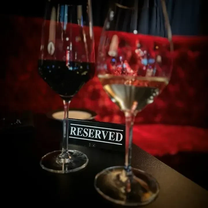Red and white wine glasses flank a "RESERVED" sign.