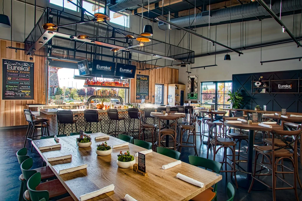 Empty modern Eureka! restaurant interior, industrial-contemporary design, prominent bar.