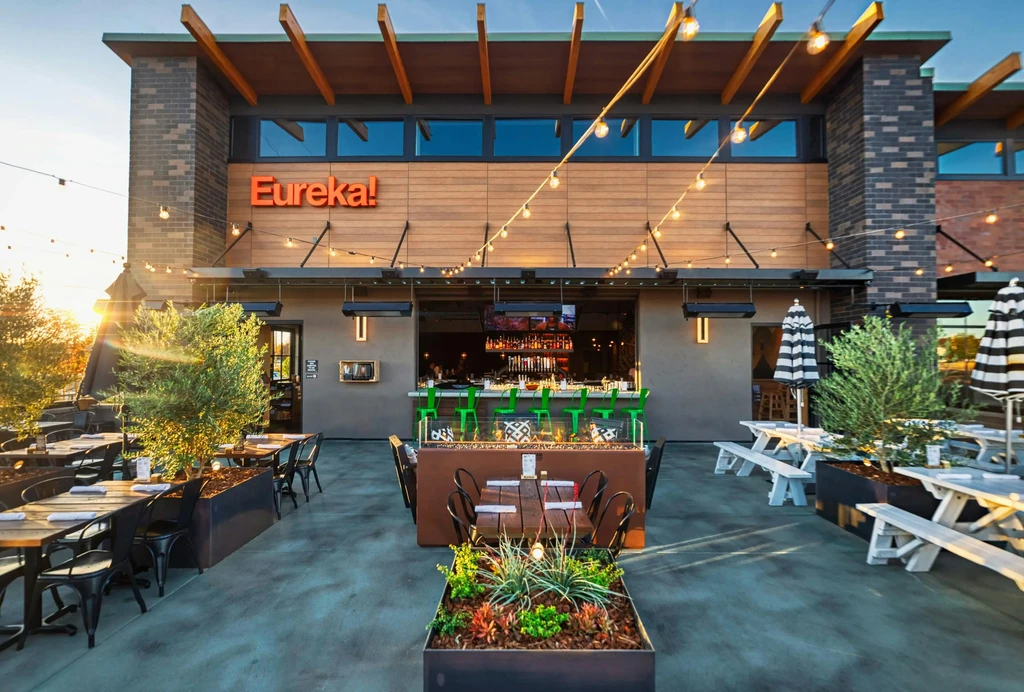 Modern Eureka! restaurant exterior with diverse, well-lit outdoor patio.