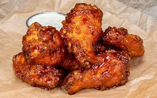 Glossy, reddish-brown glazed chicken wings on parchment paper.