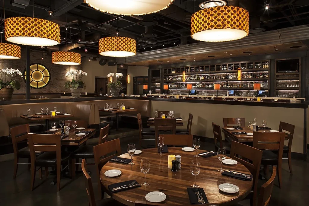 Elegant, empty restaurant with set tables, comfortable seating, and a stocked bar.