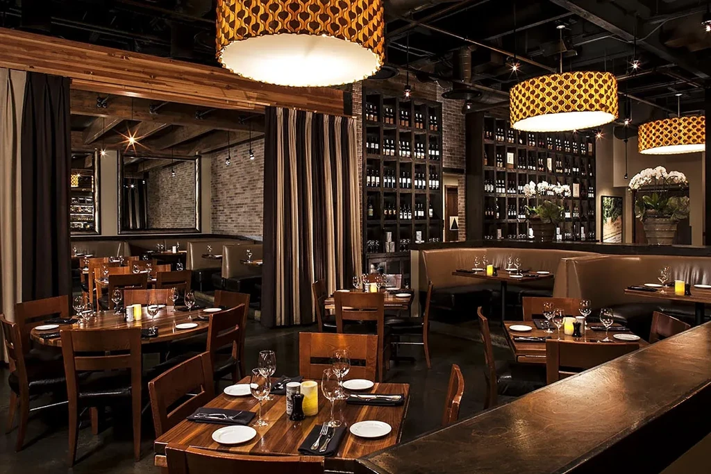 Empty modern restaurant with dark wood, leather booths, and warm lighting.