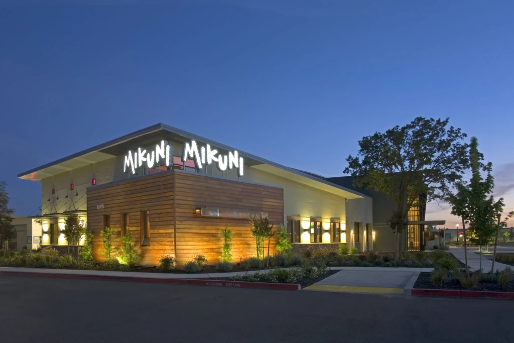 Illuminated Mikuni restaurant building with distinctive sloped roof and warm lighting.