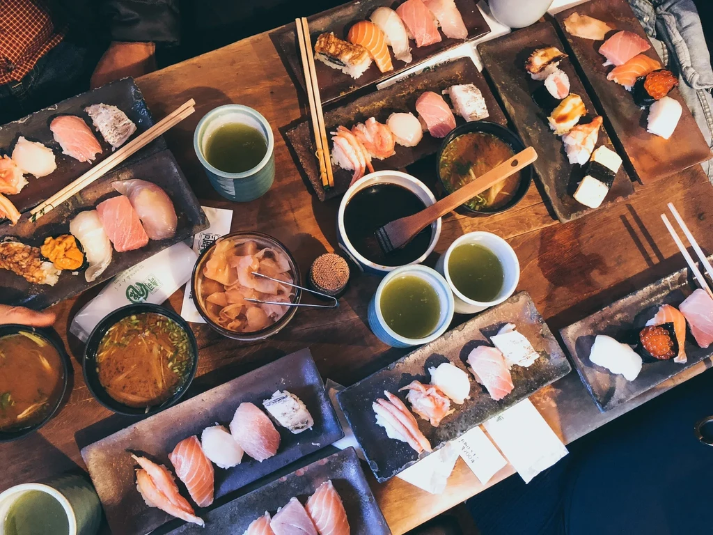Overhead view of a Japanese meal with sushi, sashimi, soup, and tea.