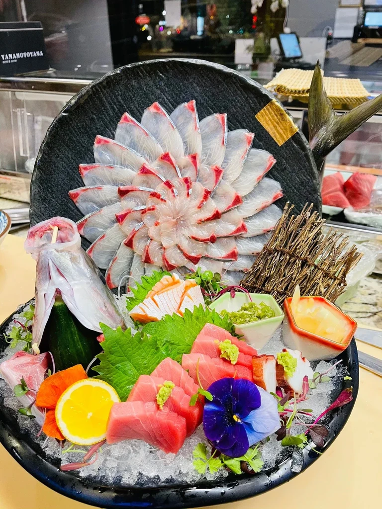 Platter of varied sashimi: fanned white fish, tuna, octopus, and fish head.