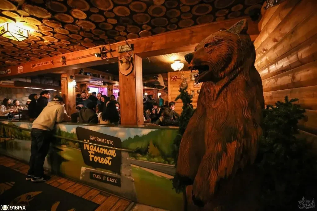 Rustic lodge restaurant interior with a large wooden bear statue.