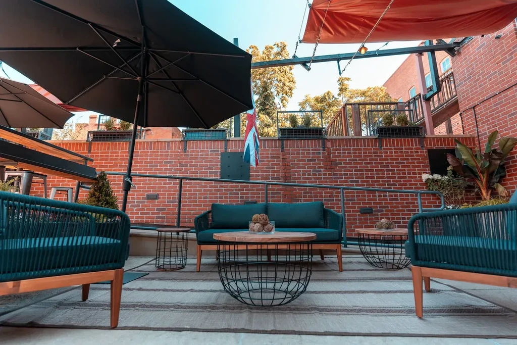 Outdoor patio with teal sofa, armchairs, Union Jack flag, and string lights.