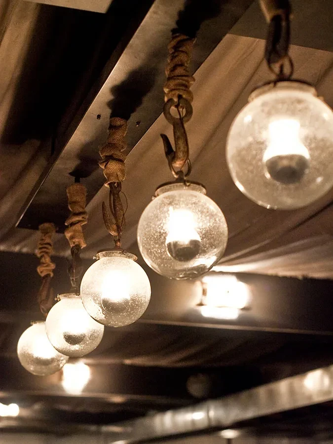 Five textured glass bulbs with warm glow hang from a dark beam.