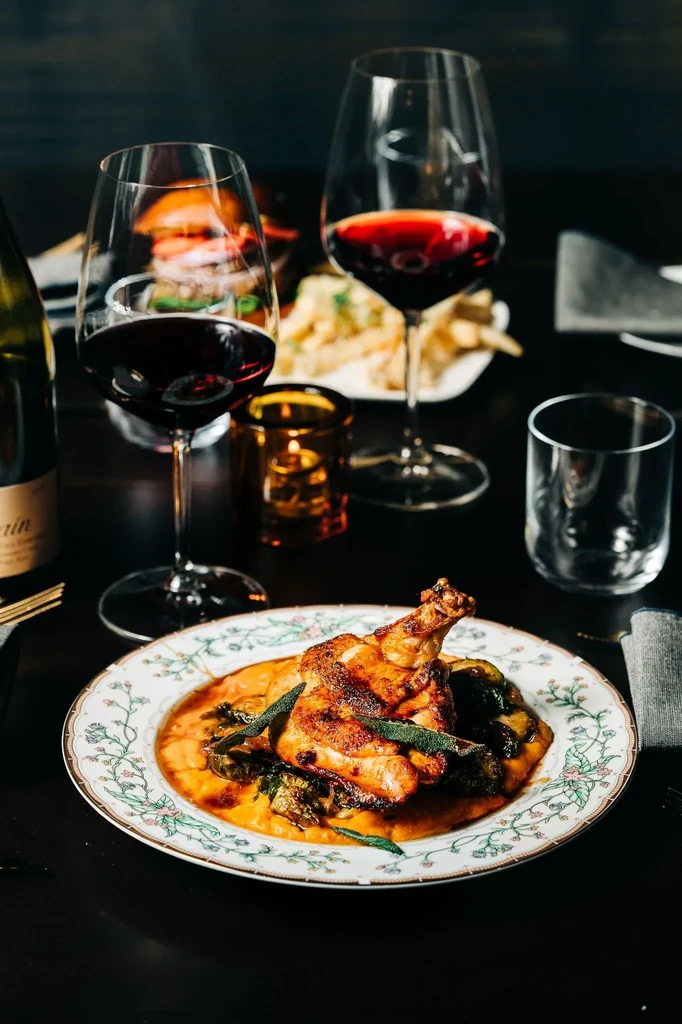 Roasted poultry with orange puree, red wine, and a lit candle.