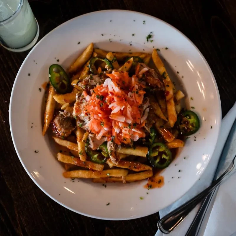 Close-up of loaded fries with pulled meat, jalapeños, and slaw.