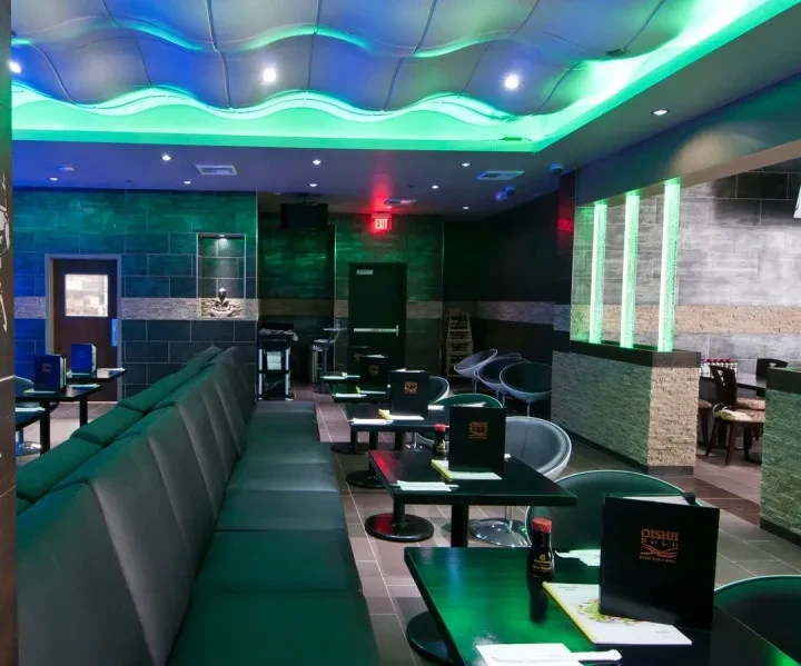 Modern restaurant with wavy ceiling and vibrant blue and green lighting.