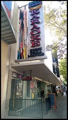 Building facade with a large red "KARAOKE SUSHI GRILL LOUNGE" sign.