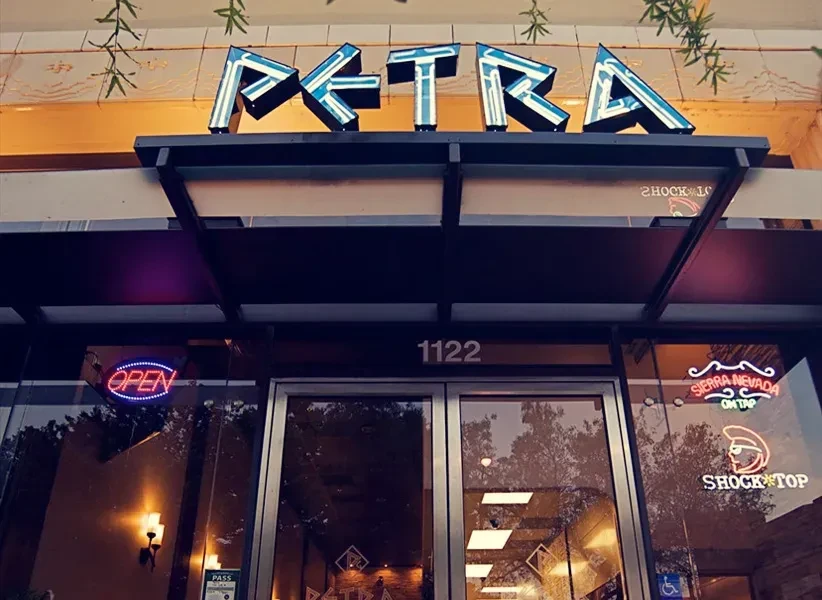 PETRA restaurant entrance at night, featuring multiple glowing neon signs.