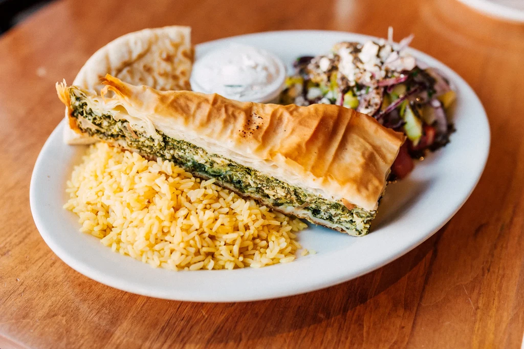 Flaky spanakopita, yellow rice, pita, tzatziki, and Greek salad.