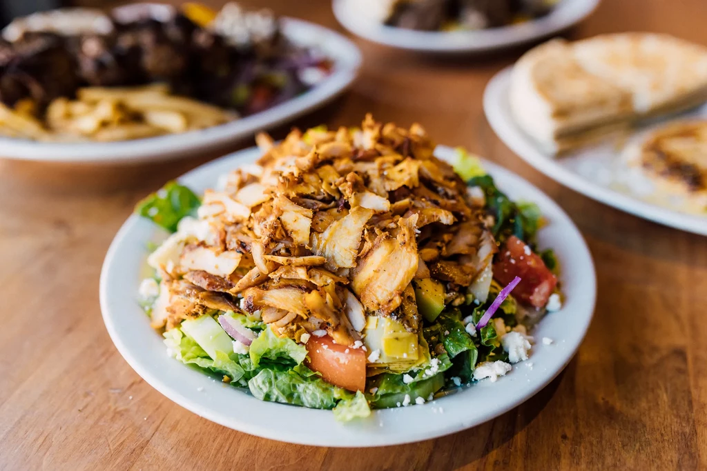 Shredded meat salad with lettuce, tomatoes, cucumber, onion, and feta.