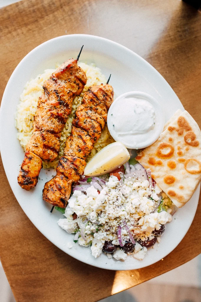 Grilled chicken skewers, yellow rice, Greek salad, tzatziki, pita.
