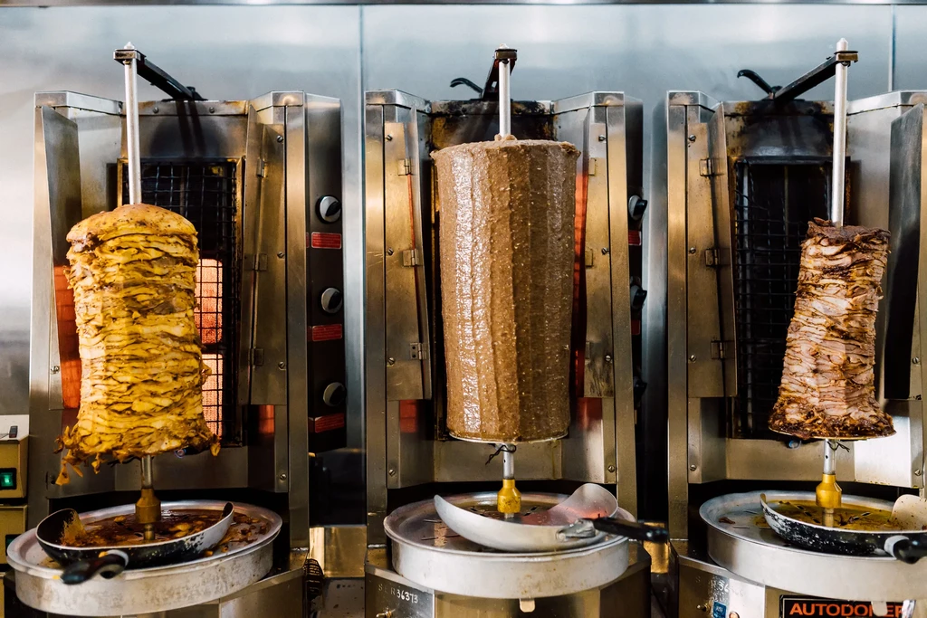 Three rotating döner kebab and shawarma in a commercial kitchen.