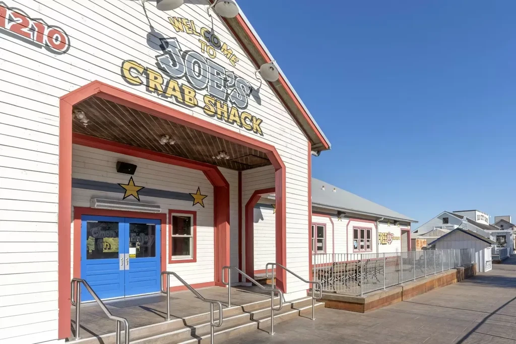 Joe's Crab Shack entrance with white siding, blue doors, and patio.