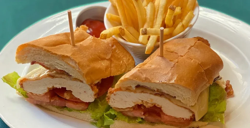 Fried chicken sandwich halves, french fries, and ketchup on a plate.