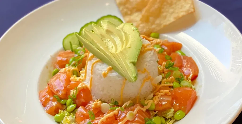 Top-down view of salmon poke bowl with avocado, edamame, rice.