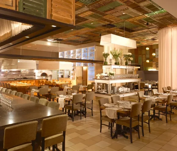Elegant restaurant interior with bar, open kitchen, and elaborate wooden ceiling.