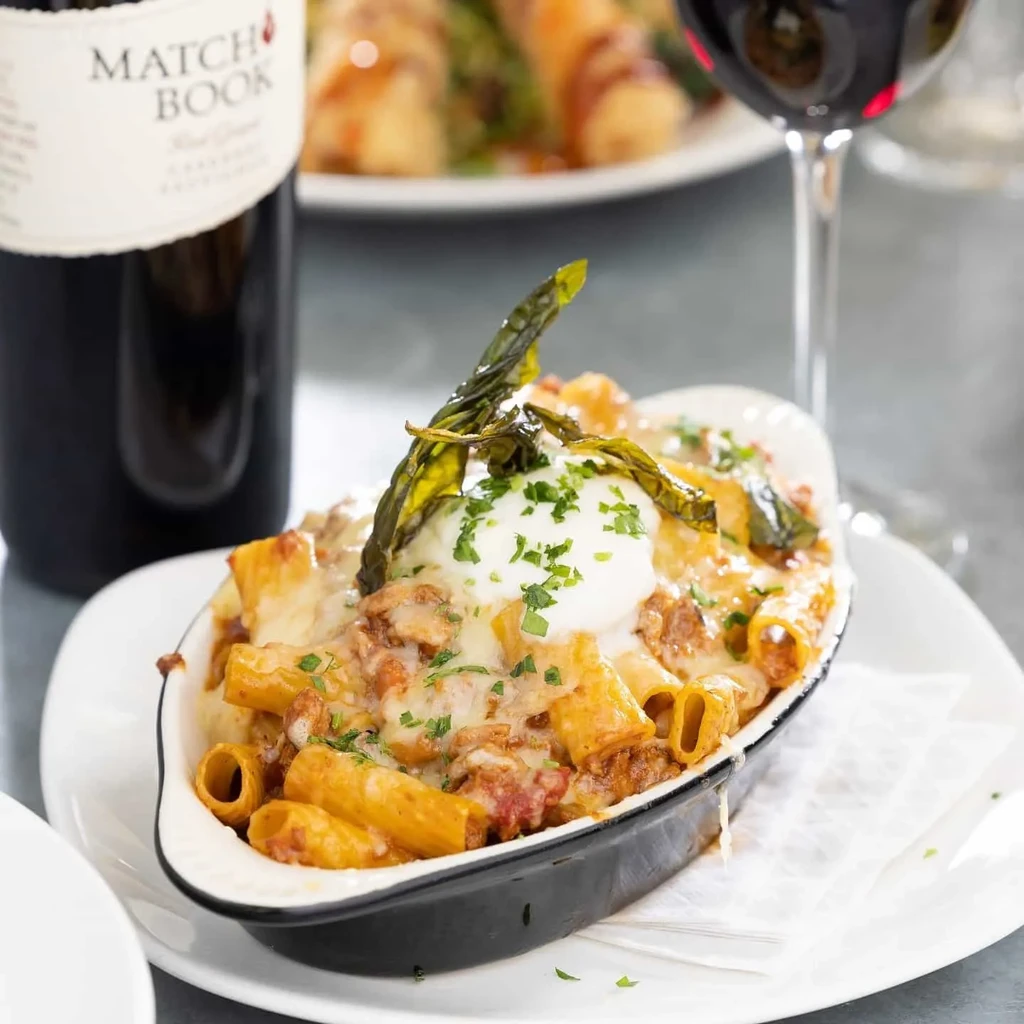 Baked rigatoni pasta with cheese, herbs, red wine, and a MATCHBOOK bottle.