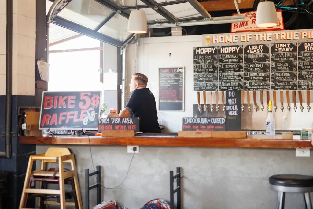 Rustic brewery bar interior with chalkboard beer menu and taps.