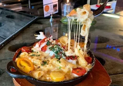 Lobster mac and cheese in skillet, fork lifting pasta with cheese pull.