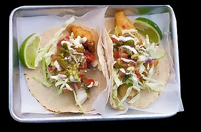 Two fish tacos with cabbage, salsa, crema and lime wedges