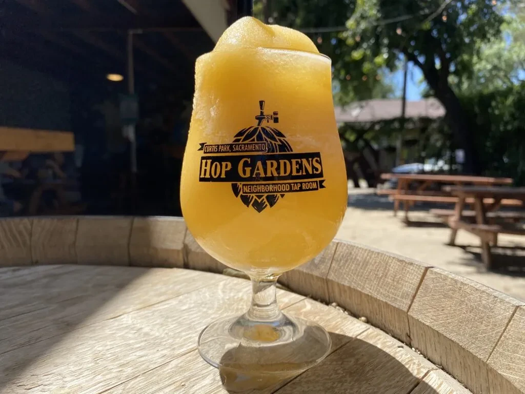 Golden slushy drink in Curtis Park Hop Gardens branded glass.