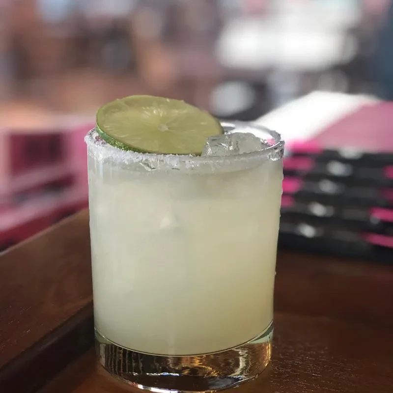 Close-up of a margarita with ice, heavily salted rim, and lime.