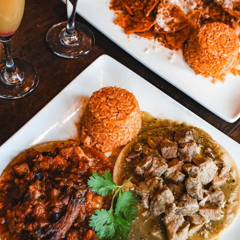 Top-down: Mexican food plates with stew, rice, and drinks.