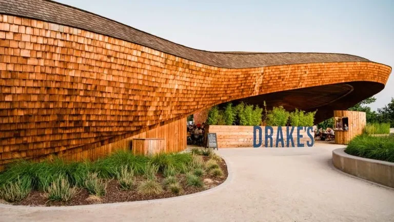 Modern, wavy wooden "DRAKE'S" building with an outdoor patio.
