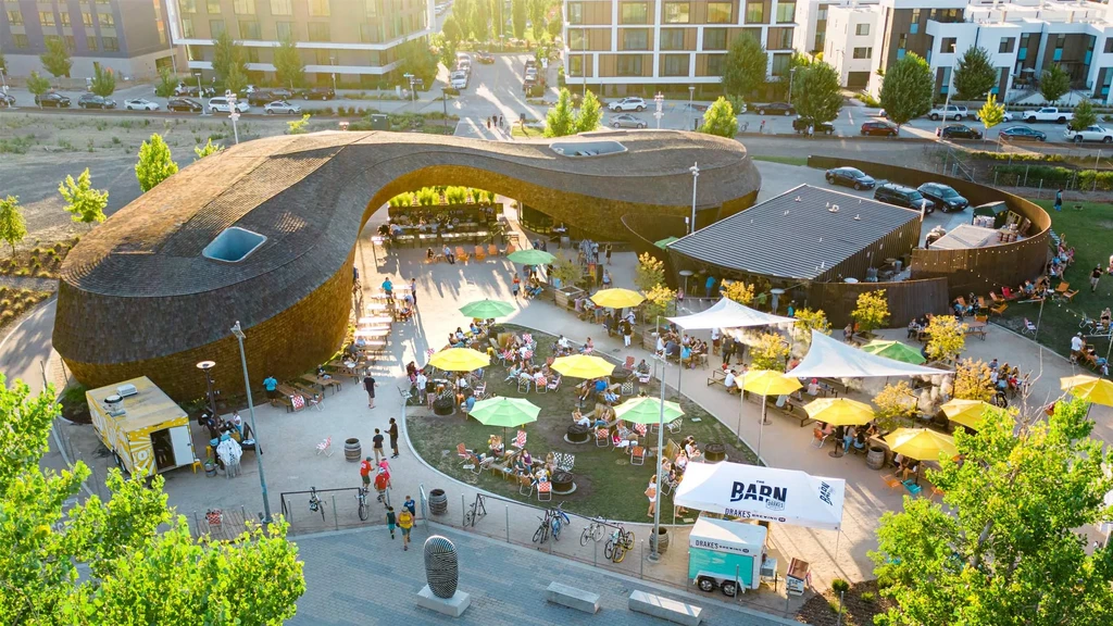 Aerial view of a curved-roof outdoor food hall bustling with patrons.