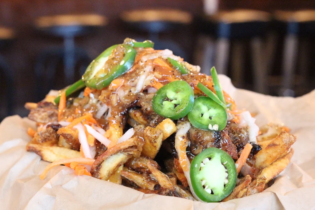 Crispy french fries generously topped with dark sauce, shredded veggies, and jalapeños.