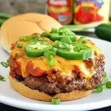 Close-up of a chili-cheese burger topped with jalapeños and green onions.