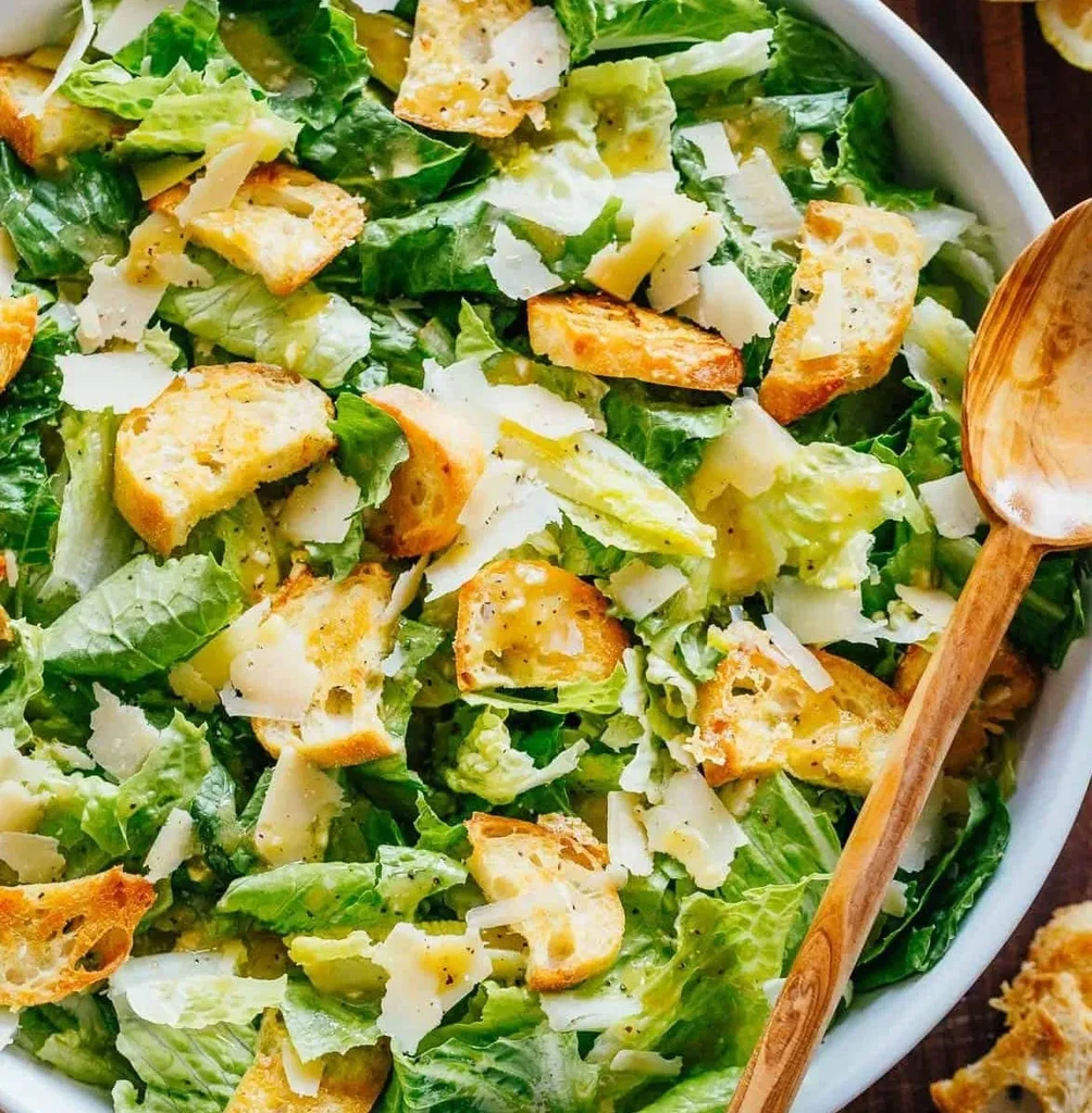 Fresh Caesar salad with croutons and Parmesan in a white bowl.