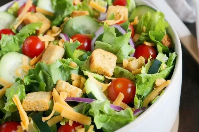 Vibrant garden salad with lettuce, tomatoes, cucumber, onion, cheese, croutons.