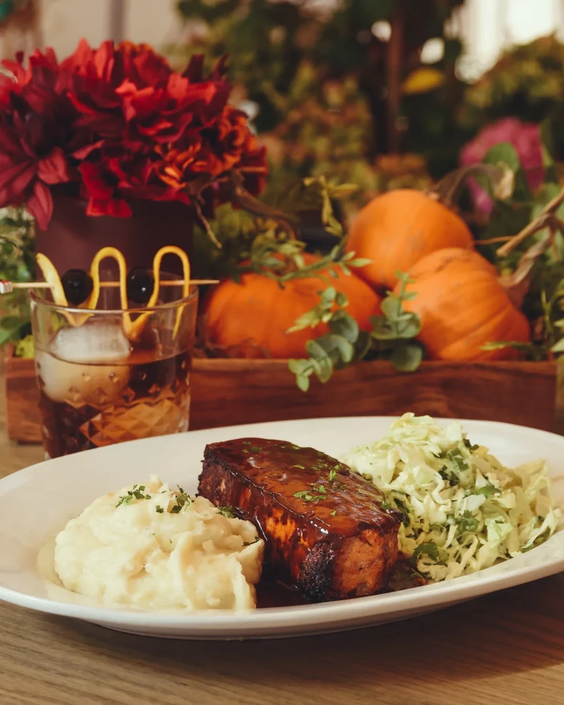 Plated meal, garnished drink, and autumnal decor.