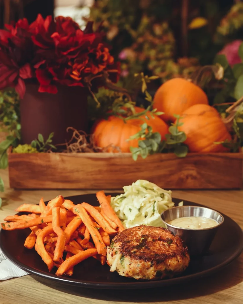 Fried patty meal with sweet potato fries, coleslaw, and autumnal decor.
