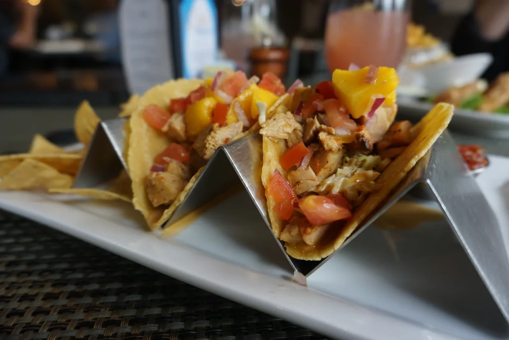 Two colorful grilled chicken tacos with mango salsa and chips.