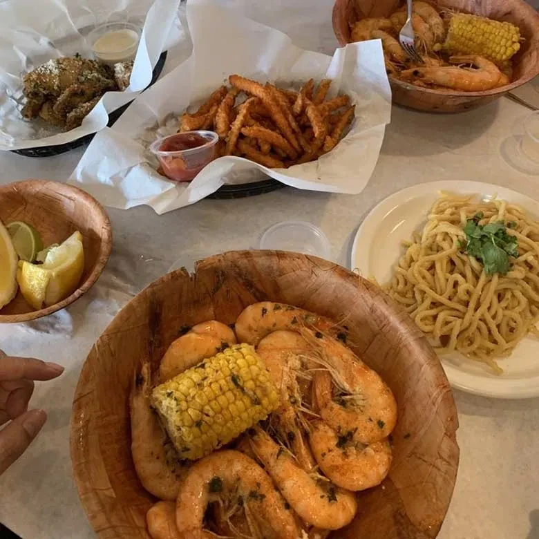 A spread of shrimp, sweet potato fries, noodles, and fried chicken.