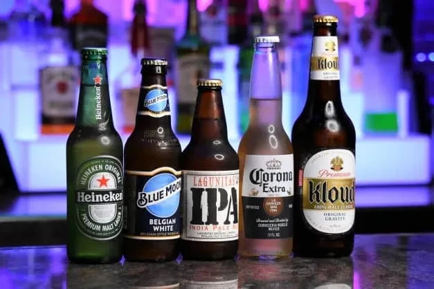 Heineken, Blue Moon, Lagunitas, Corona, Kloud beer bottles on a bar.