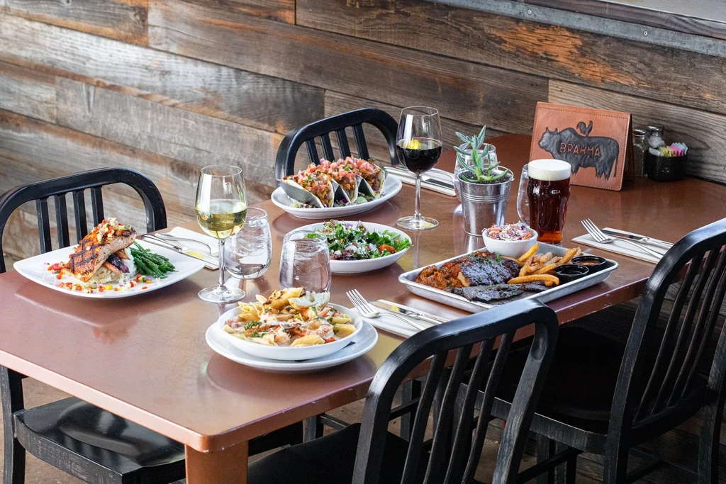 Rustic restaurant table filled with diverse food and many drinks.