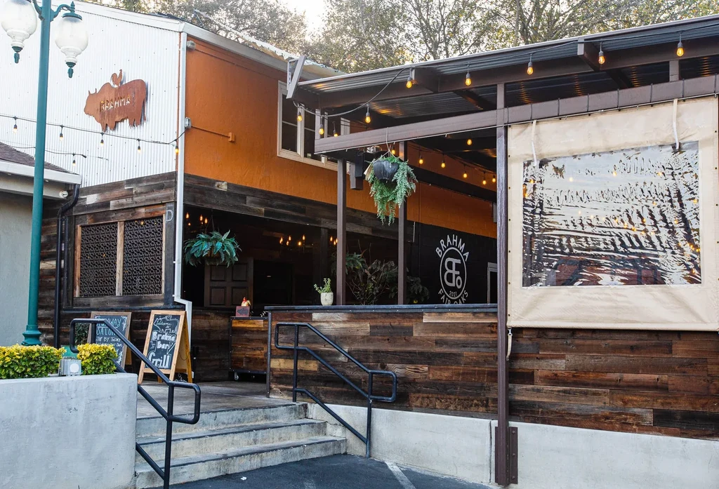 Exterior of Brahma Bar Grill with multi-textured facade and lit patio.